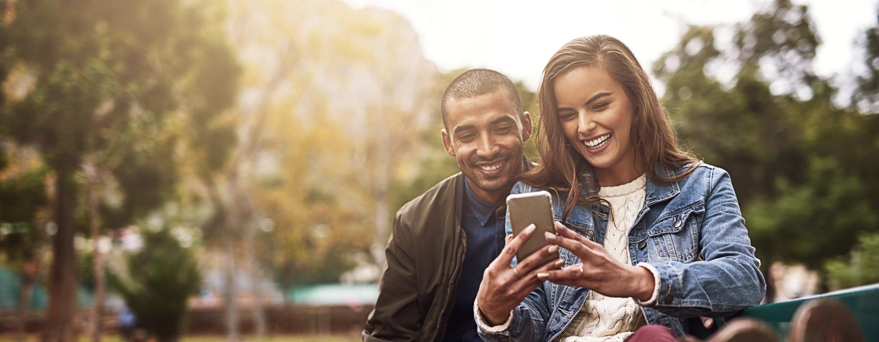 a man and woman sitting on a bench and smiling at the camera