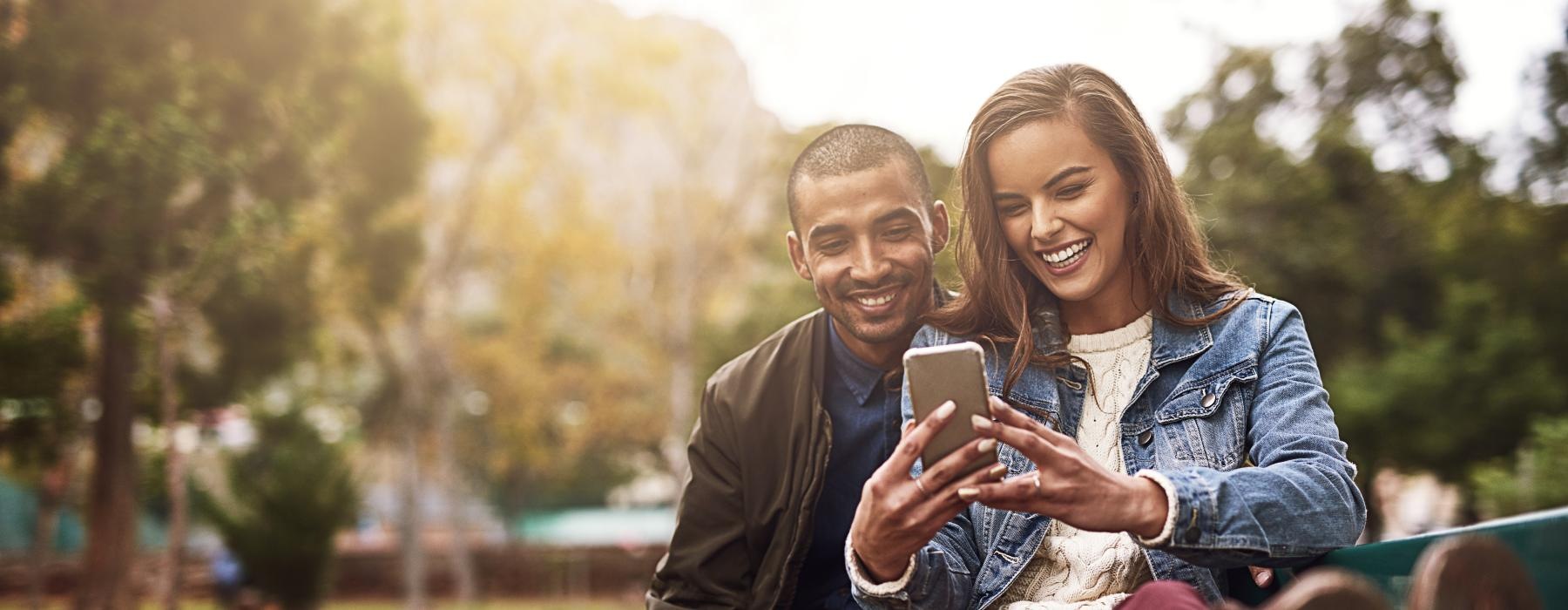 a man and woman sitting on a bench and smiling at the camera